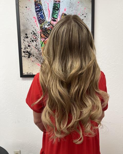 After: the same client with long, full, blended blonde waves from a weft extension install